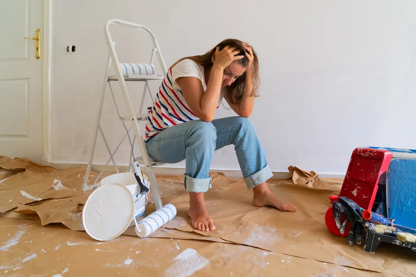 An empty freshly painted room with a ladder, paint cans and drop cloths on the floor